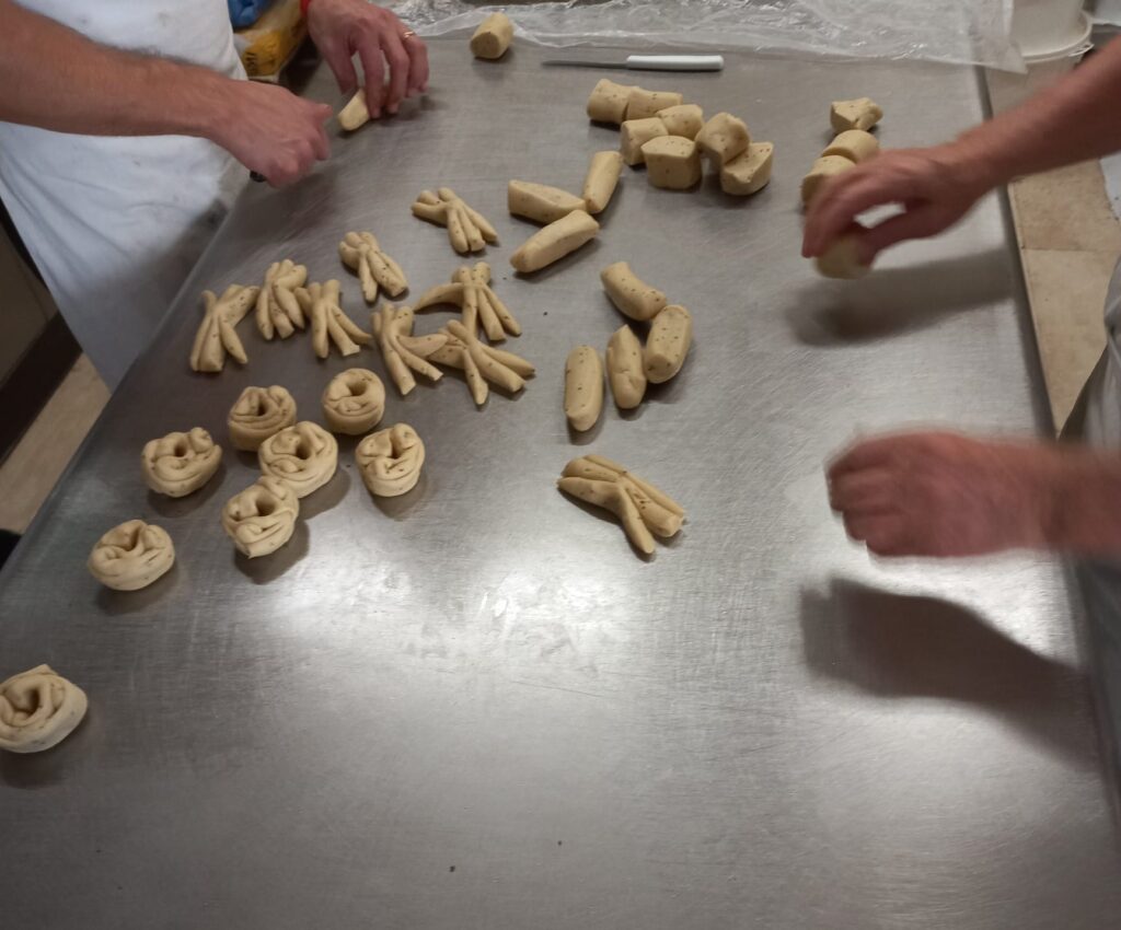 Mani che modellano pasta fresca artigianale nel laboratorio de Il Tortellino